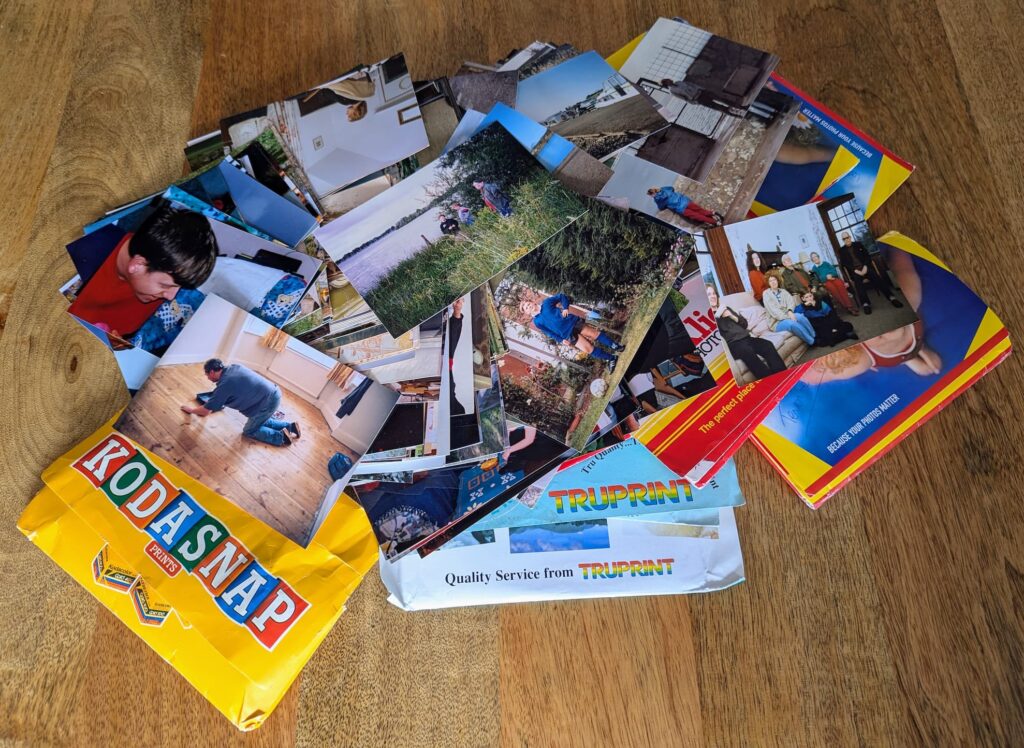 A large pile of loose prints and packets of photos on a table.